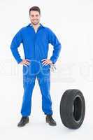 Smiling mechanic with hands on hips standing by tire