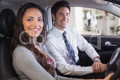 Female driver at the wheel sitting in her car with salesperson