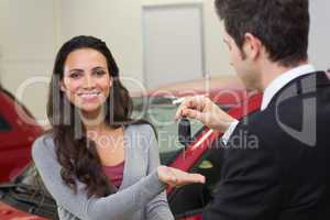 Businessman giving car key while shaking a customer hand