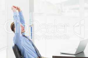 Focused businessman stretching at his desk