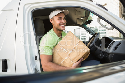 Smiling delivery driver in his van holding parcel