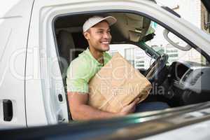 Smiling delivery driver in his van holding parcel