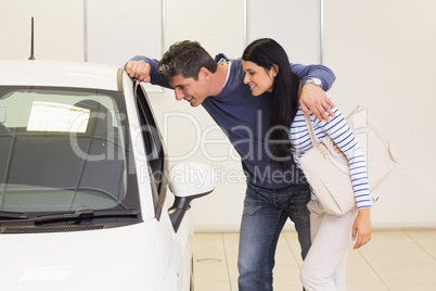 Smiling couple looking inside a car