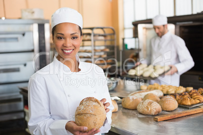 Pretty baker smiling at camera with loaf