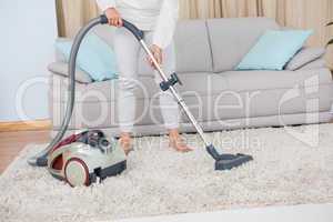 Woman using vacuum cleaner on rug