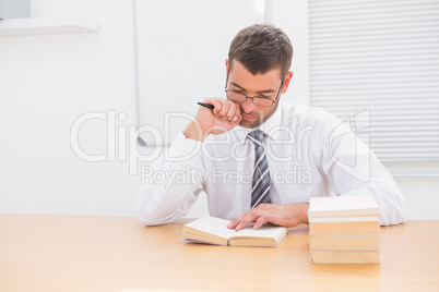 Businessman sitting at desk reading books