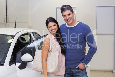 Smiling couple standing in front of a car