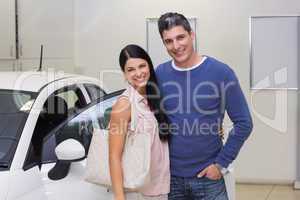 Smiling couple standing in front of a car