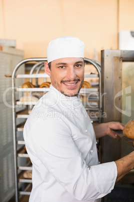 Happy baker taking out fresh loaves