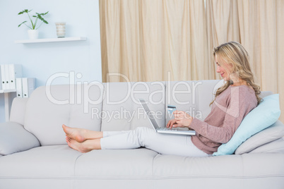 Smiling blonde shopping online with laptop