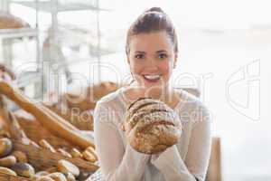 Pretty brunette showing loaf of bread