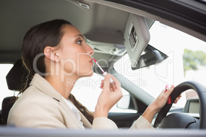 Businesswoman using mirror to put on lip gloss