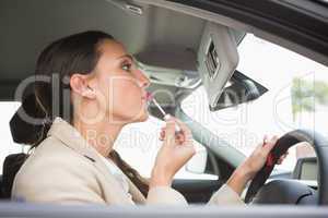 Businesswoman using mirror to put on lip gloss