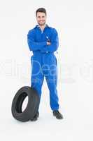 smiling mechanic with arms crossed standing by tire