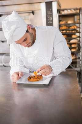 Focused baker putting flower on the pastry