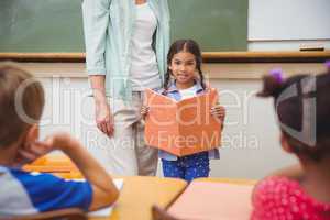 Cute pupil smiling at camera during class presentation