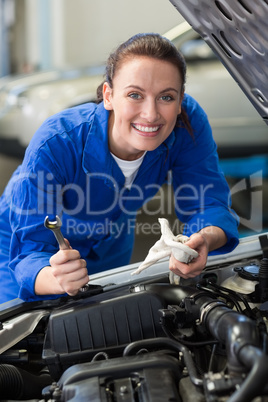 Mechanic smiling at the camera fixing engine