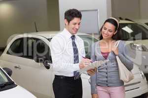 Salesperson showing clipboard to sign to customer