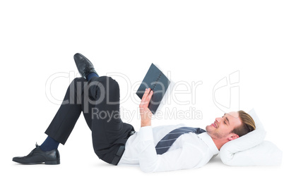 Relaxed businessman lying and reading book