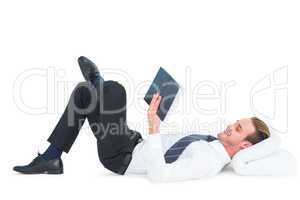 Relaxed businessman lying and reading book