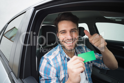 Young man smiling at camera showing card