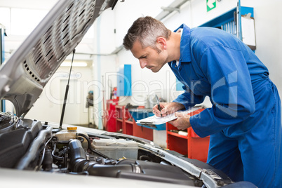 Mechanic examining under hood of car