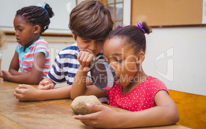 Cute pupils looking through magnifying glass