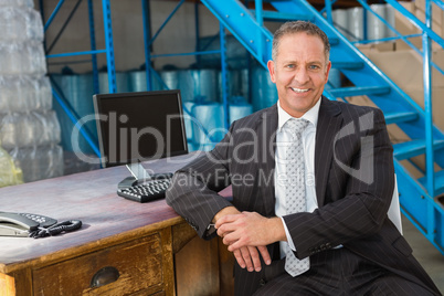 Smiling warehouse manager with computer