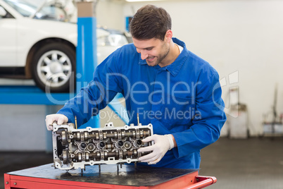 Smiling mechanic working on engine