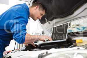 Mechanic using laptop on car