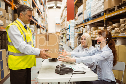 Manager wearing yellow vest giving box to his colleague