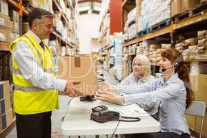 Manager wearing yellow vest giving box to his colleague