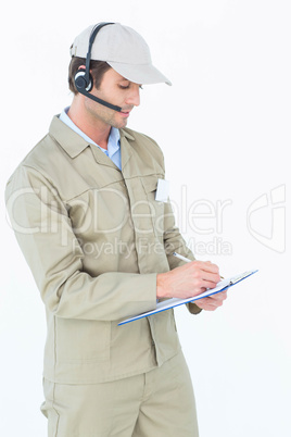 Delivery man using headphones while writing on clipboard