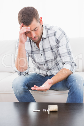 Hungover man with his medicine laid out on coffee table