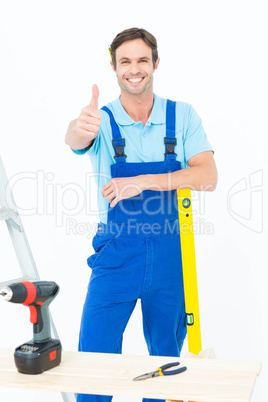 Carpenter leaning on spirit level while gesturing thumbs up