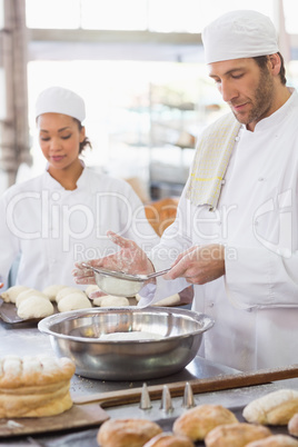 Baker sieving flour into a bowl