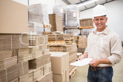 Smiling warehouse worker with clipboard