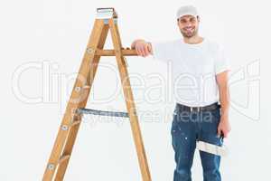 Happy man with paint roller standing by ladder