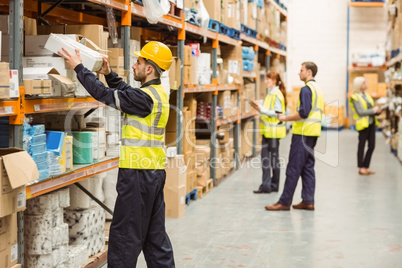 Warehouse worker taking package in the shelf