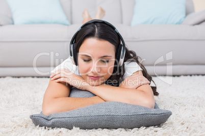 Pretty brunette lying on the rug listening to music