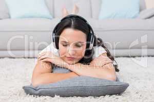 Pretty brunette lying on the rug listening to music