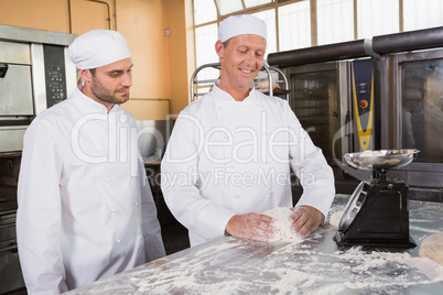 Baker looking his colleague kneading dough