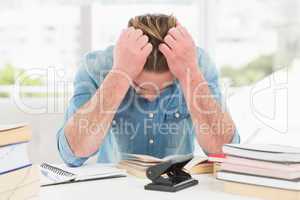 Stressed casual businessman studying at his desk