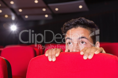 Young man watching a scary film