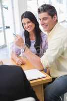 Smiling couple holding credit card to buy a car