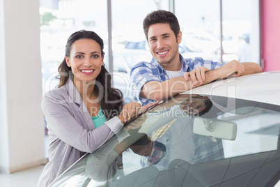 Smiling couple leaning on car