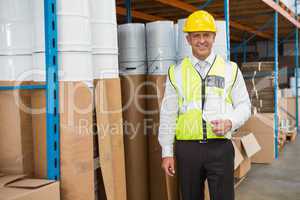 Warehouse manager wearing hard hat holding clipboard