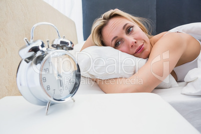 Beautiful blonde in bed with alarm clock