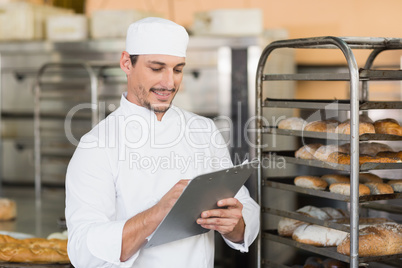 Smiling baker writing on clipboard