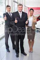 Smiling business team standing while giving thumbs up